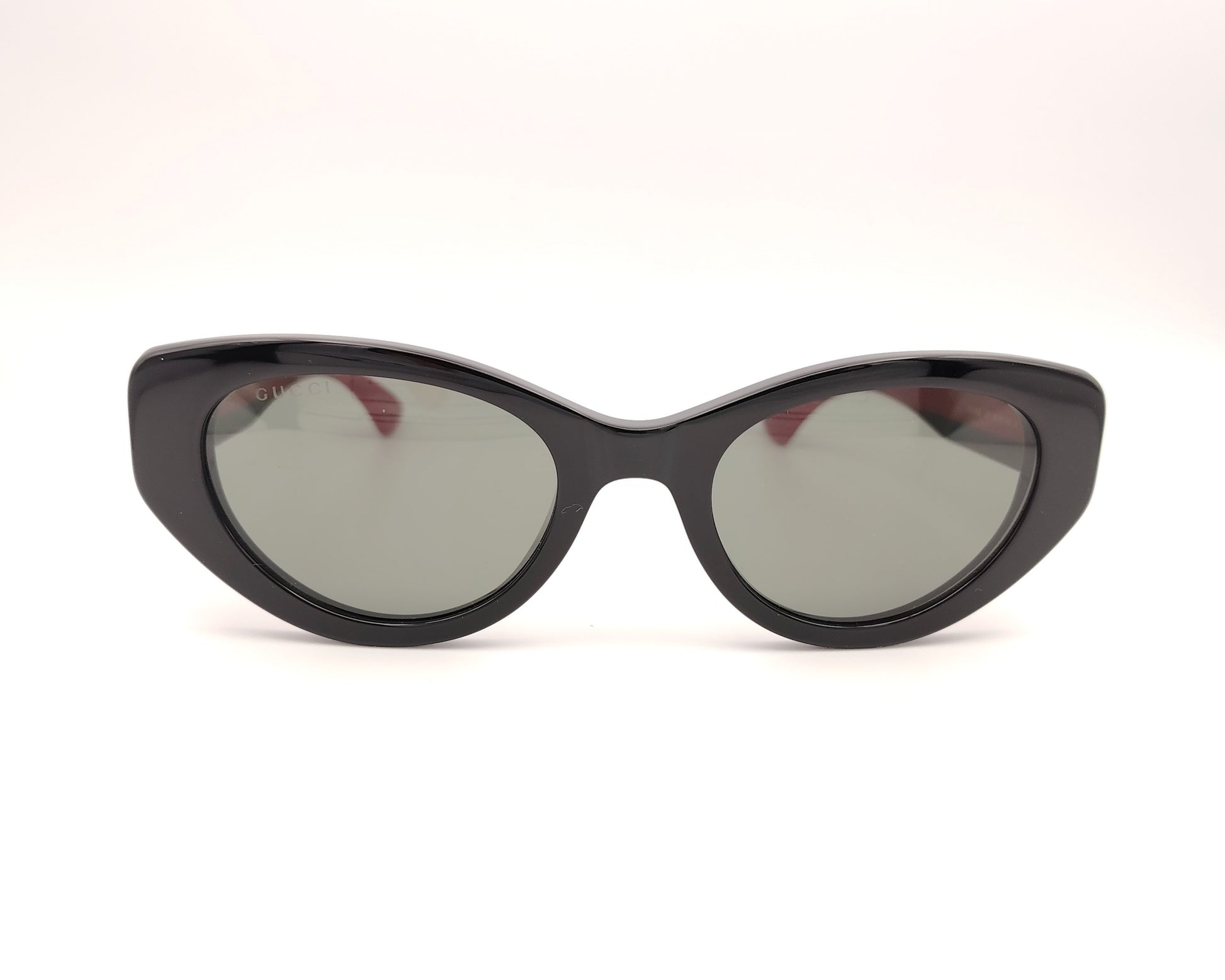 gafas de sol negras estilo cat eye con patillas verdes y rojas y logo dorado

