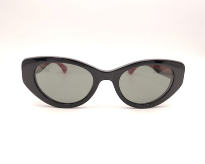 gafas de sol negras estilo cat eye con patillas verdes y rojas y logo dorado

