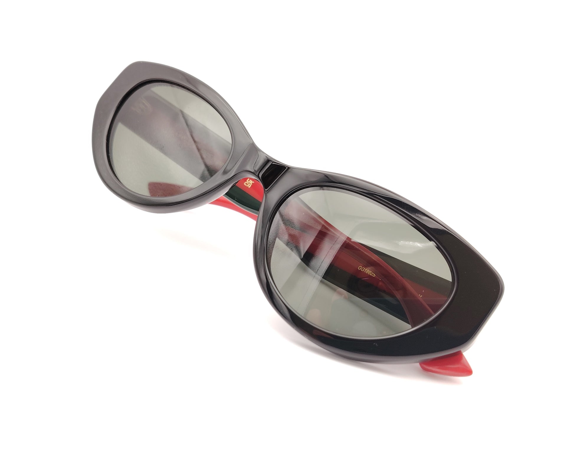 gafas de sol negras estilo cat eye con patillas verdes y rojas y logo dorado

