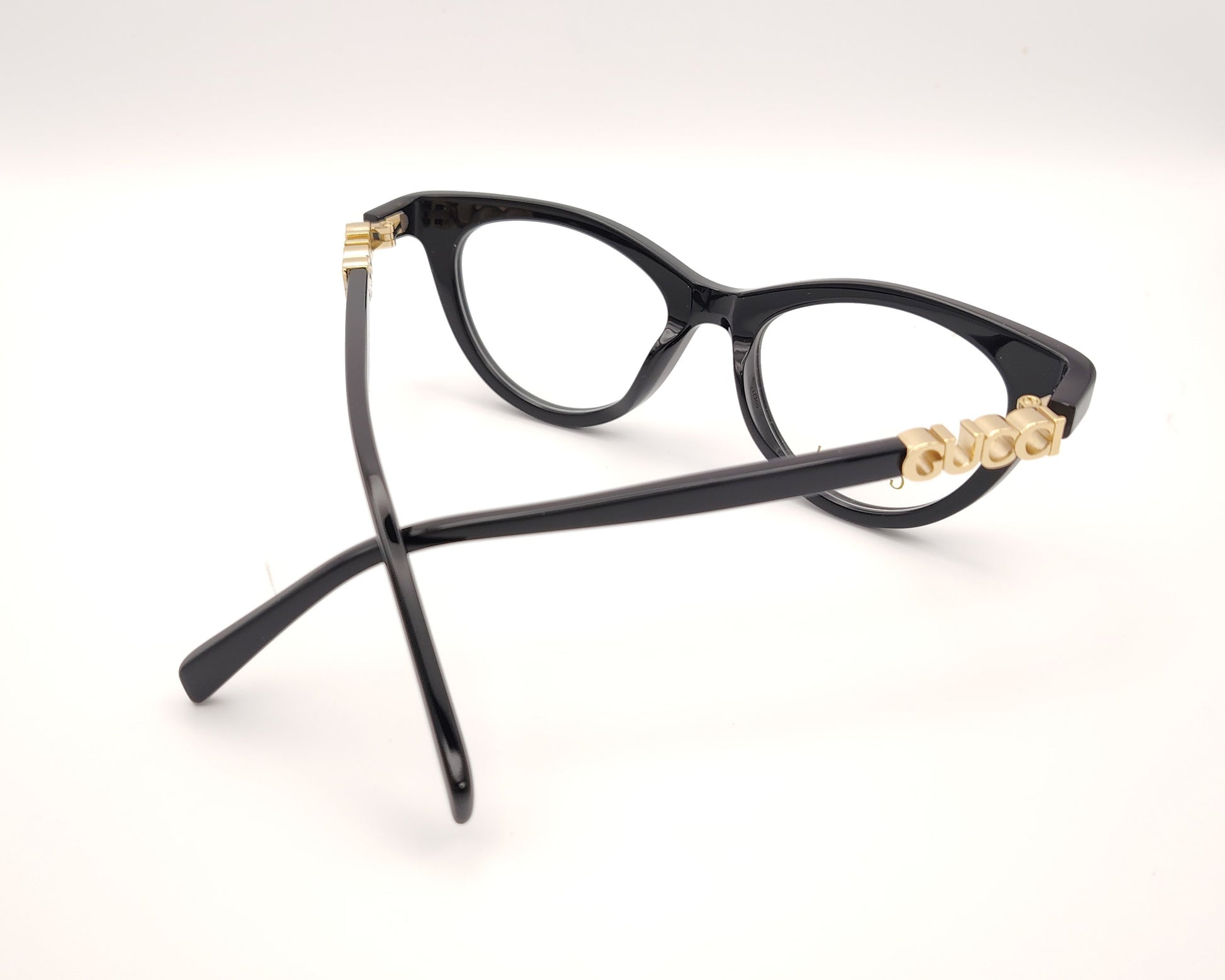 gafas gucci negras redondeadas con logo dorado en varilla