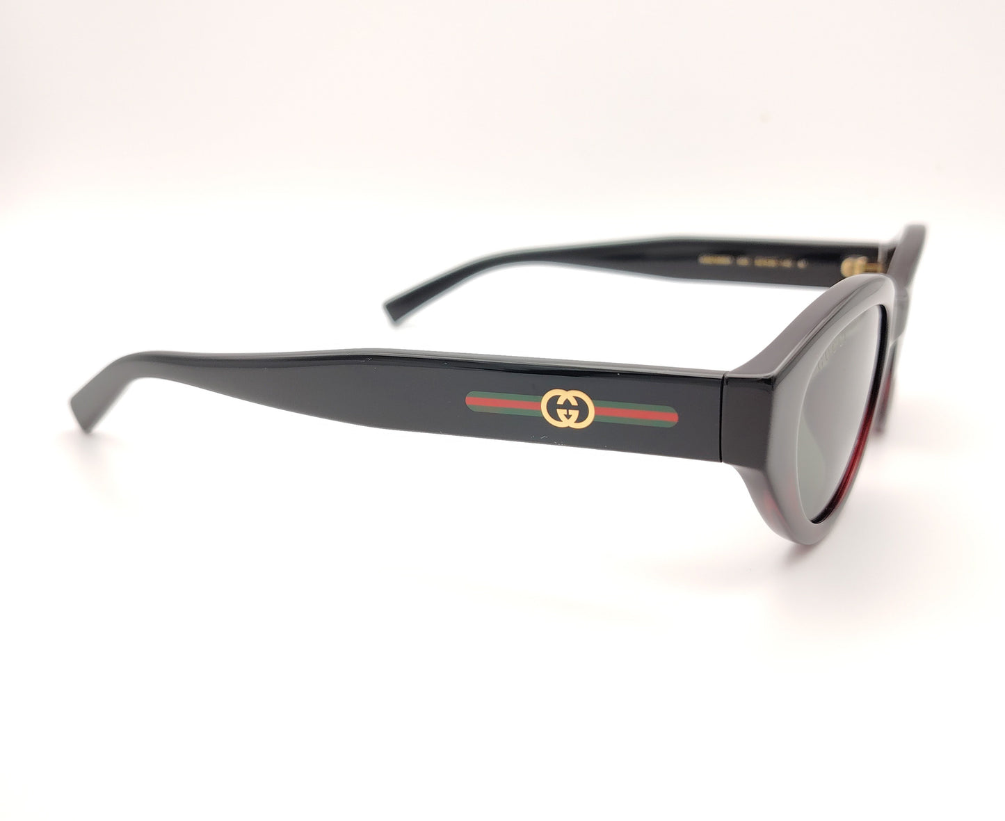 gafas de sol gucci ovaladas negras con detalle burdeos y varillas con logo dorado y bandas verde y roja