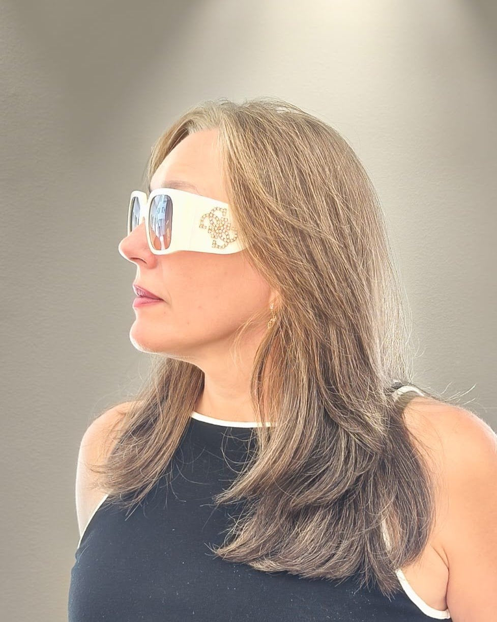 gafas de sol grandes con montura blanca rectangular, lentes degradadas en lila y detalle decorativo en las varillas