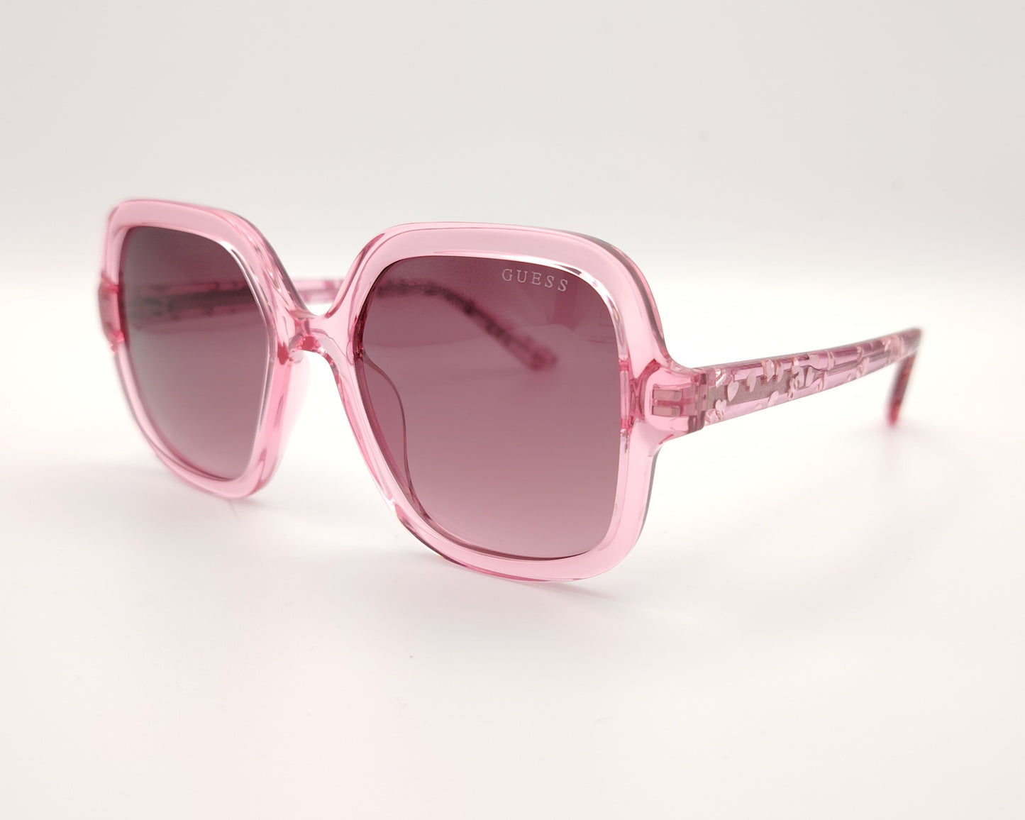 gafas de sol guess rosas translúcidas con lentes malva degradadas y corazones en la varilla