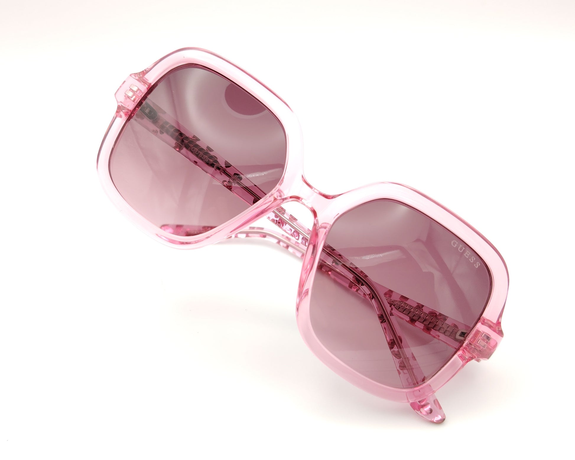 gafas de sol guess rosas translúcidas con lentes malva degradadas y corazones en la varilla
