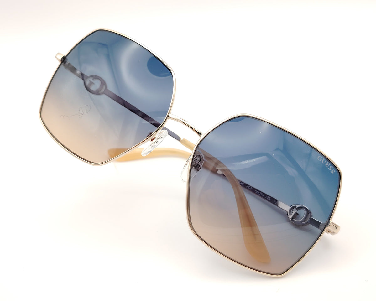 gafas guess cuadradas con montura dorada fina y lentes degradadas azul y marrón
