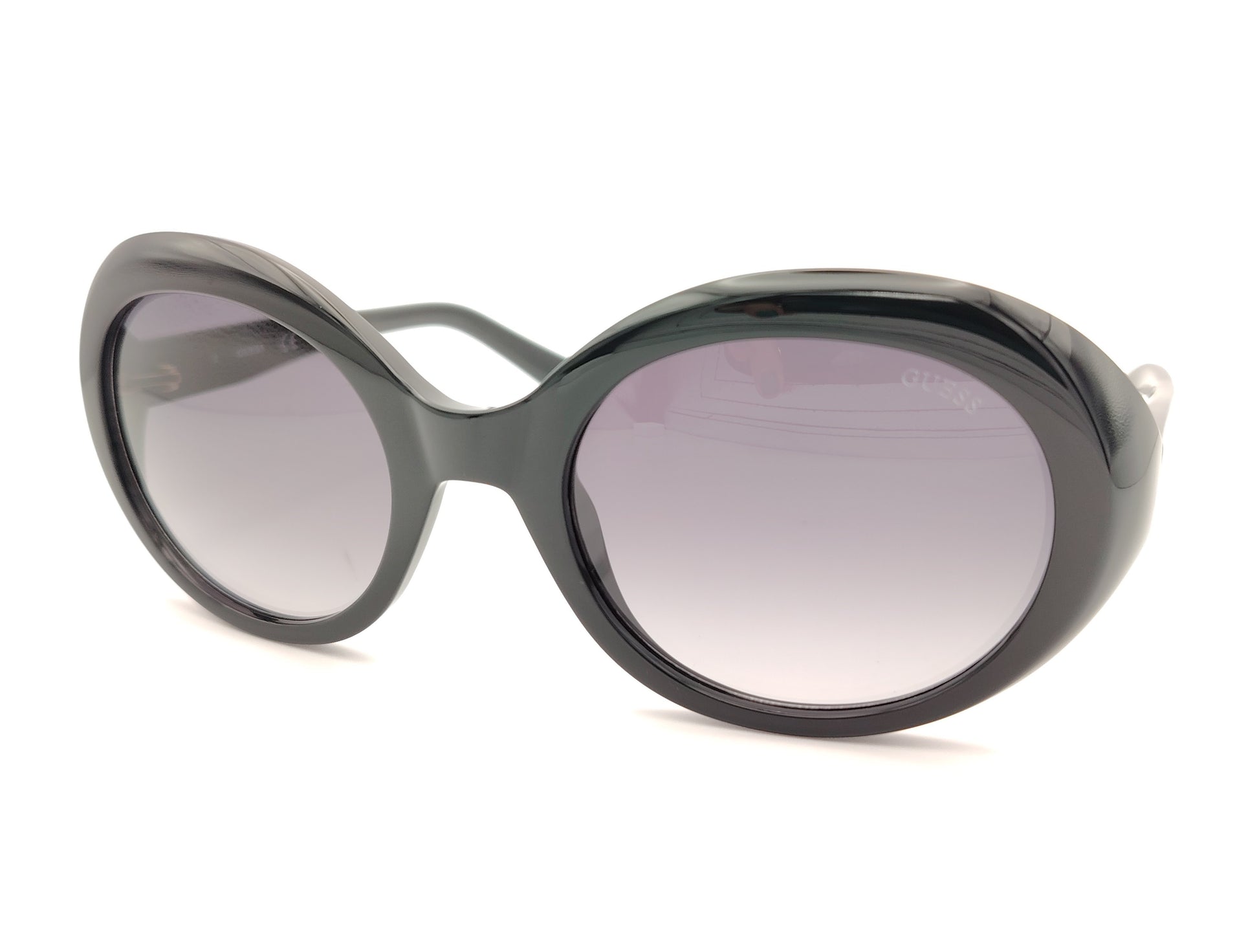 gafas guess negras ovaladas con lentes gris violáceo degradadas y logo dorado en la patilla
