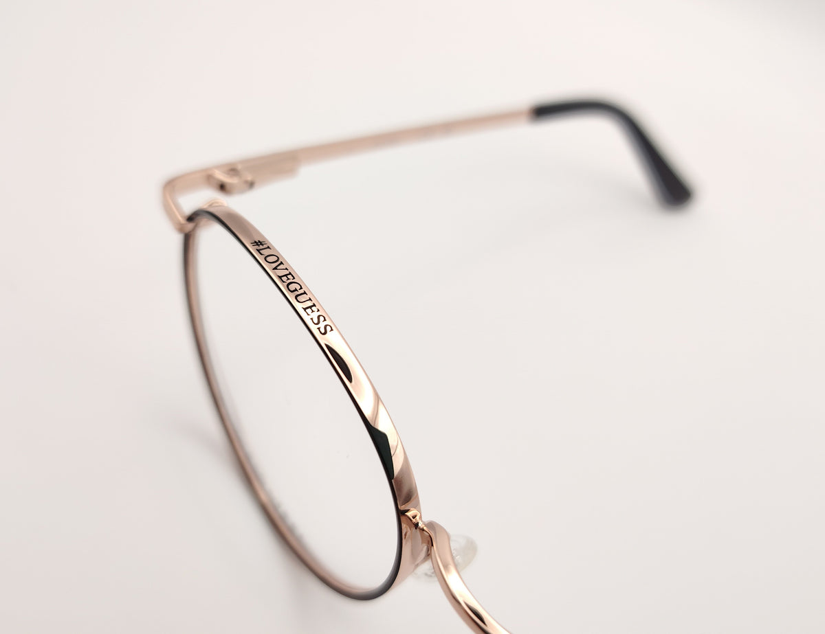 gafas de vista guess con montura redonda de metal dorado con el perfil de los aros en negro