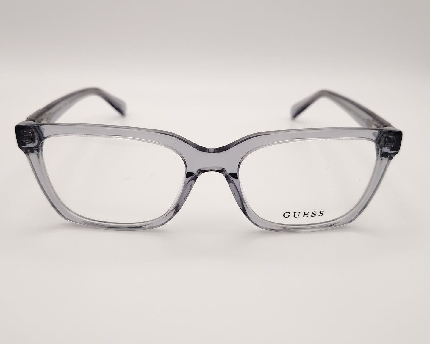 guess gu50132 020 montura elegante en acetato gris transparente con un diseño rectangular, estructura ligera y cómoda perfecta para el día a día detalles metálicos en las varillas que aportan un toque distintivo ideal para un look moderno y versátil