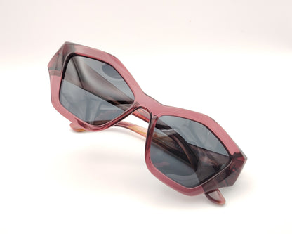 gafas de sol pentagonales con montura rosa translúcida y lentes oscuras polarizadas