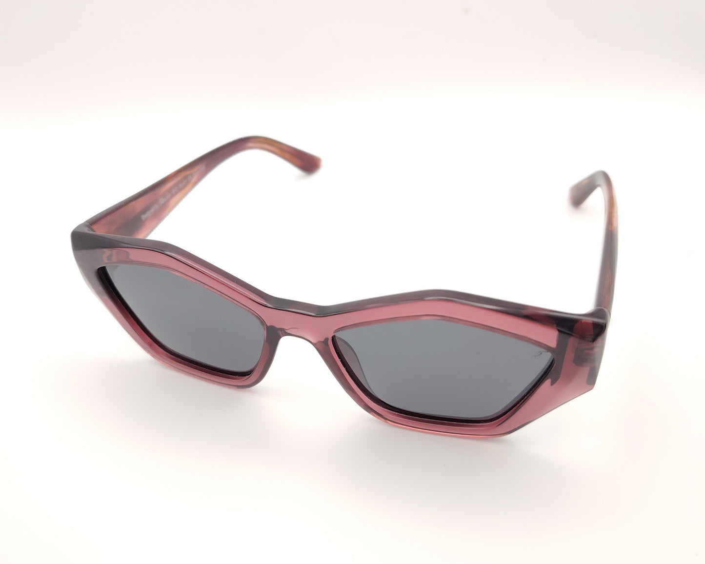 gafas de sol pentagonales con montura rosa translúcida y lentes oscuras polarizadas