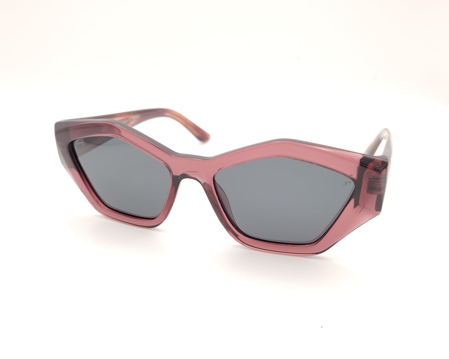 gafas de sol pentagonales con montura rosa translúcida y lentes oscuras polarizadas