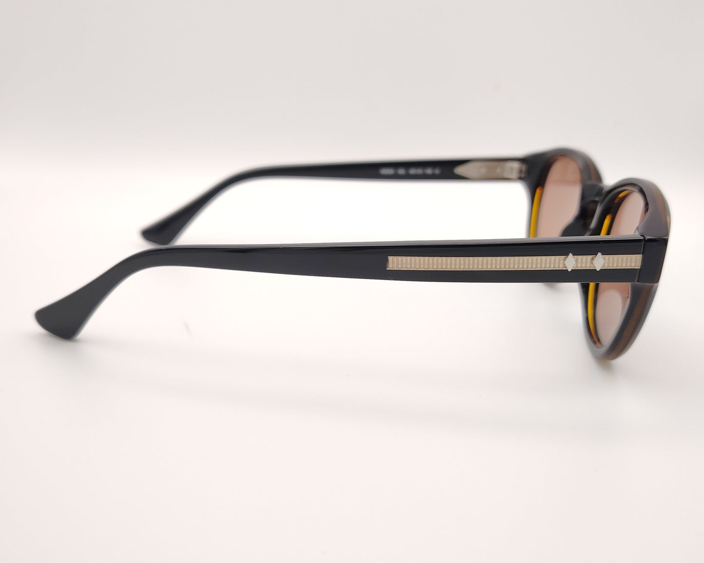 gafas de sol web eyewear con montura de acetato negro, puente metálico dorado y lentes marrones
