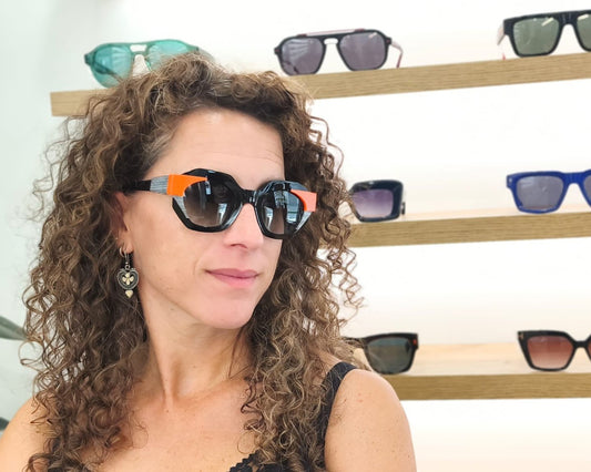 gafas de sol angulosas con montura negra, detalles naranjas y rayas blancas