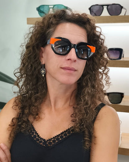 gafas de sol angulosas con montura negra, detalles naranjas y rayas blancas
