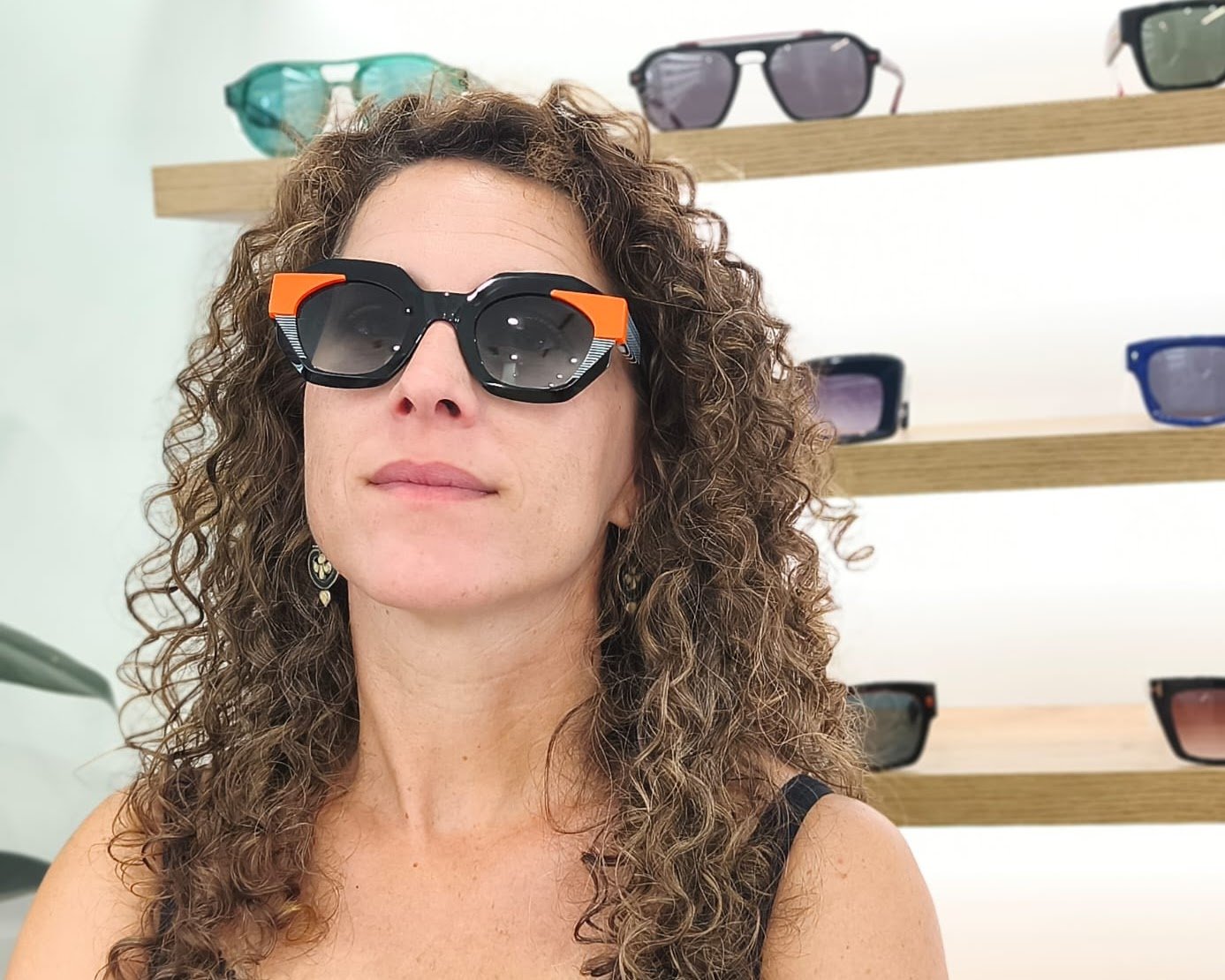 gafas de sol angulosas con montura negra, detalles naranjas y rayas blancas