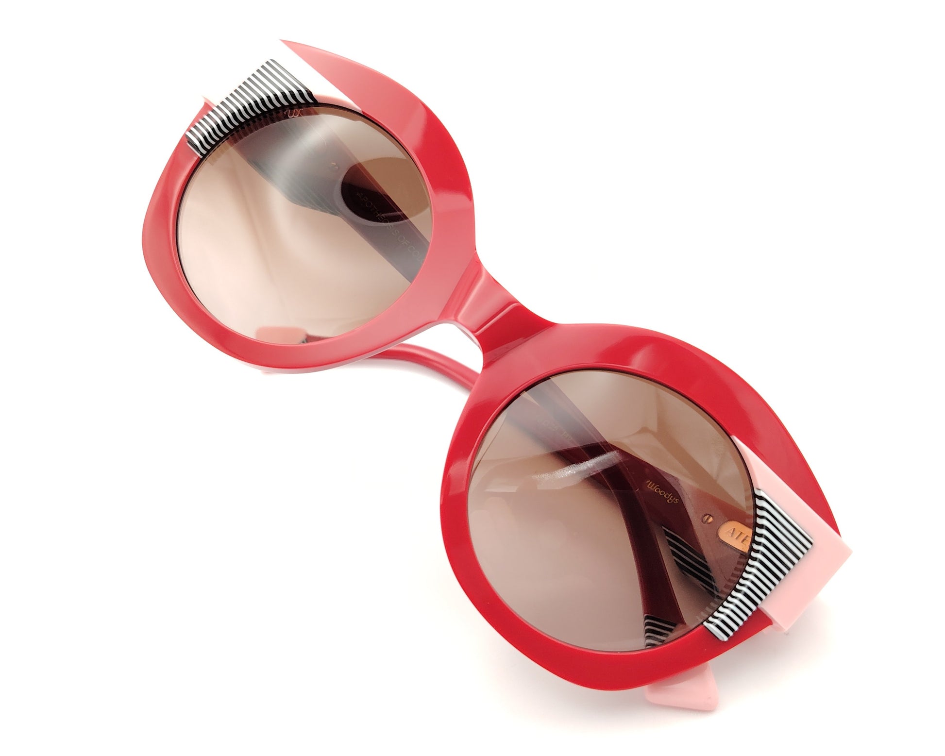 gafas de sol redondas rojas con detalles en rosa claro y líneas gráficas en blanco y negro