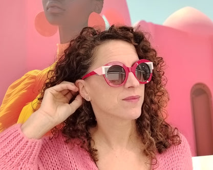gafas de sol redondas rojas con detalles en rosa claro y líneas gráficas en blanco y negro