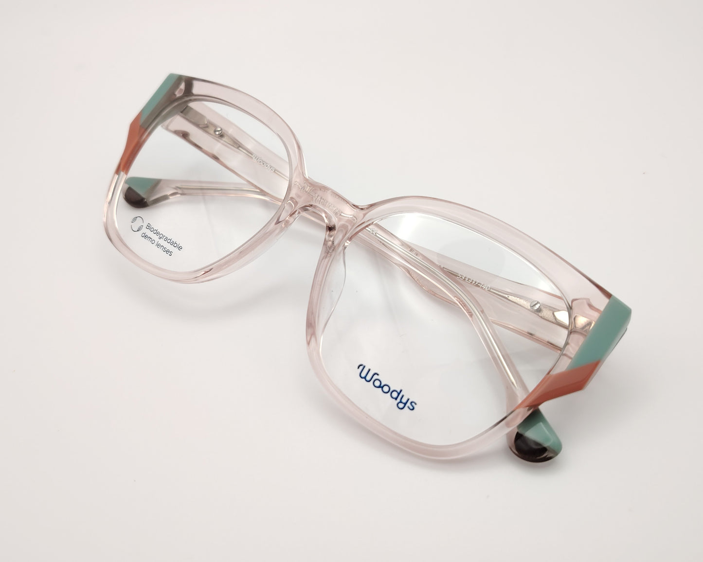 gafas graduadas woodys dagmar 04 con montura geométrica en acetato translúcido de color rosa clarito detalles en las esquinas en tonos verde y coral 